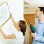 Person hanging wooden wall art with measuring tape