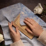 Close-up of wooden wall art being dusted with a soft cloth